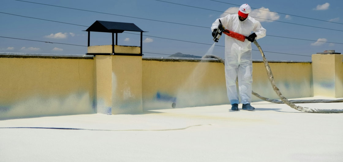 a-man-in-a-white-coverall-spray-painting-a-roof.jpg a man in a white coverall spray painting a roof