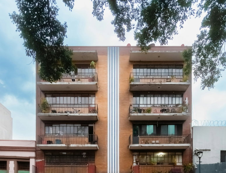 Modern apartment building with shops on ground floor.