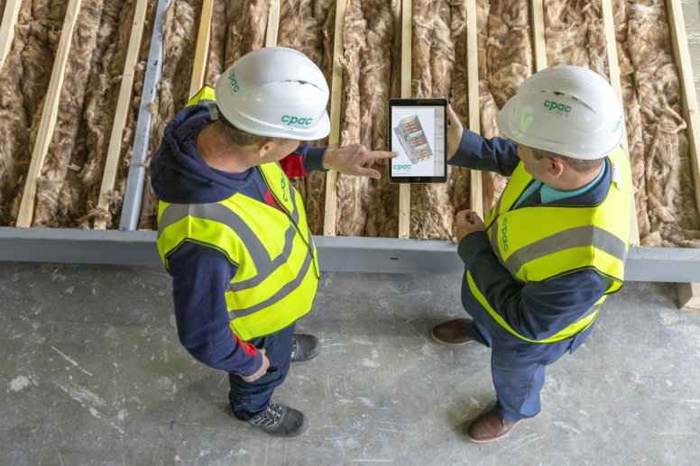 two-construction-workers-review-plans-on-a-tablet-.jpg Two construction workers review plans on a tablet.